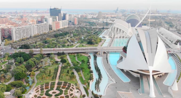 Aerial view of the City of Arts and Sciences in Valencia, featuring modern architecture, green gardens, and nearby city buildings.
