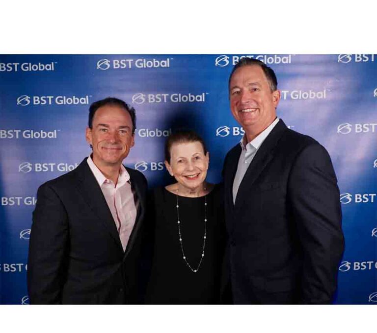 Three people standing in front of a BST Global backdrop, smiling at the camera.