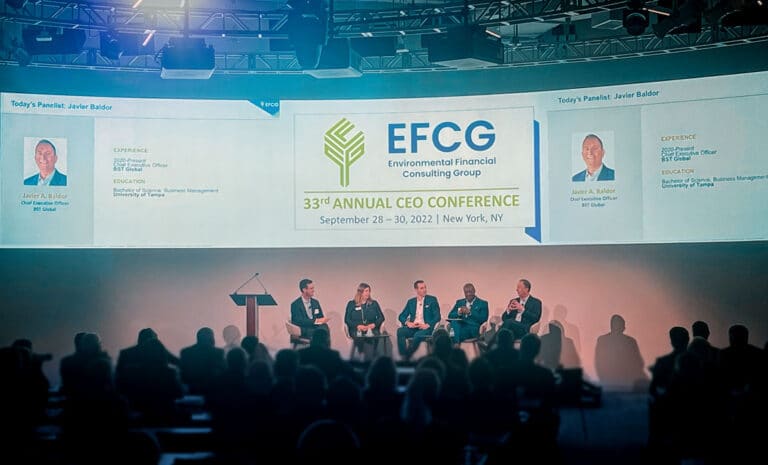 Panel discussion on stage at the 33rd Annual EFCG CEO Conference in New York, with five seated participants and a presentation screen in the background.