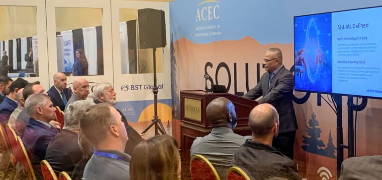 A speaker presents information on AI and ML to an audience at a conference, with a screen displaying related graphics.