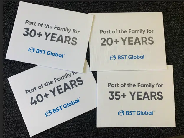 Signs on a carpet displaying "Part of the Family for 30+ Years," "20+ Years," "40+ Years," and "35+ Years" with the BST Global logo.