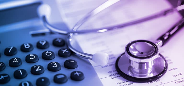 Stethoscope and calculator on financial documents, symbolizing the intersection of healthcare and finance.