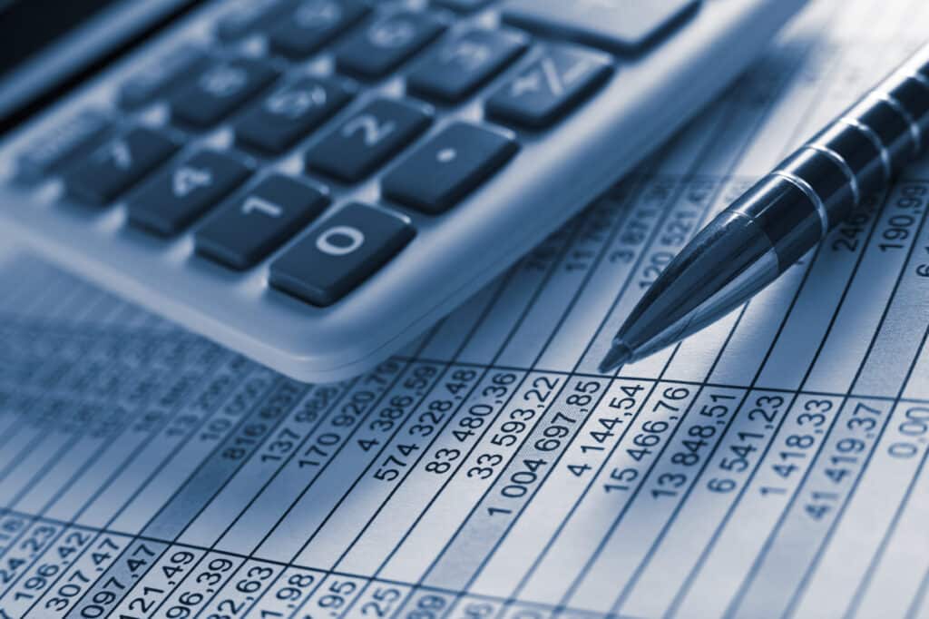 Calculator and pen resting on a financial spreadsheet with numbers and columns.