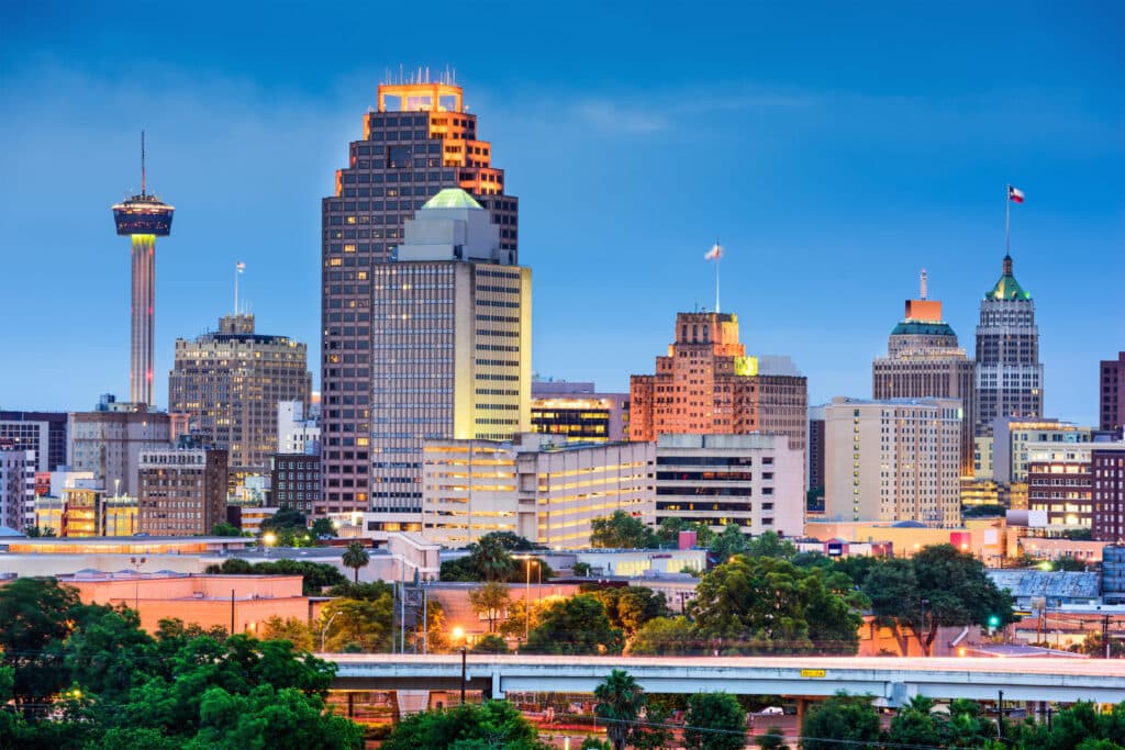 San Antonio skyline at dusk featuring a mix of modern and historic buildings, with the prominent Tower of the Americas in the background.