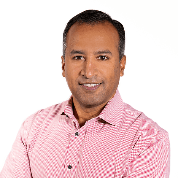 Person in a pink checkered shirt standing against a white background.