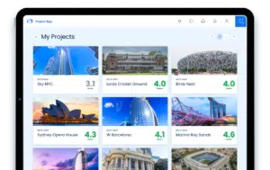 Tablet screen displaying a project management app with images of landmarks like Sky NYC, Birds Nest, and Marina Bay Sands, each with a score rating.