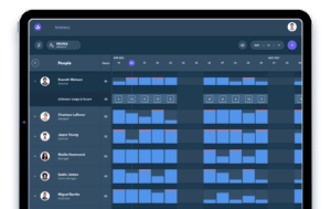 Tablet displaying a scheduling app with a calendar grid, showing people’s names alongside their work hours and shifts highlighted in blue and red blocks for April and May 2023.