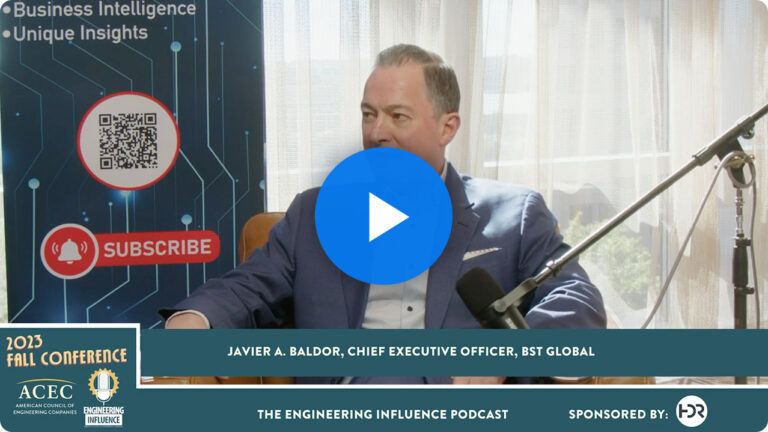 A person in a business suit speaks into a microphone with a conference banner and text promoting a podcast.