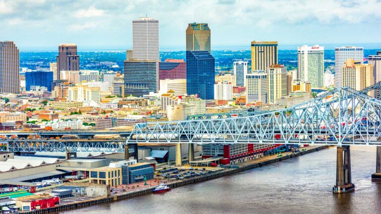 Aerial view of a city skyline with a prominent bridge spanning a river in the foreground.