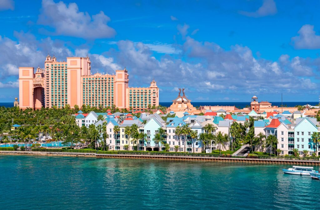 Oceanfront view of Atlantis Paradise Island Resort in the Bahamas, with its iconic towers and colorful beachfront buildings under a clear blue sky.