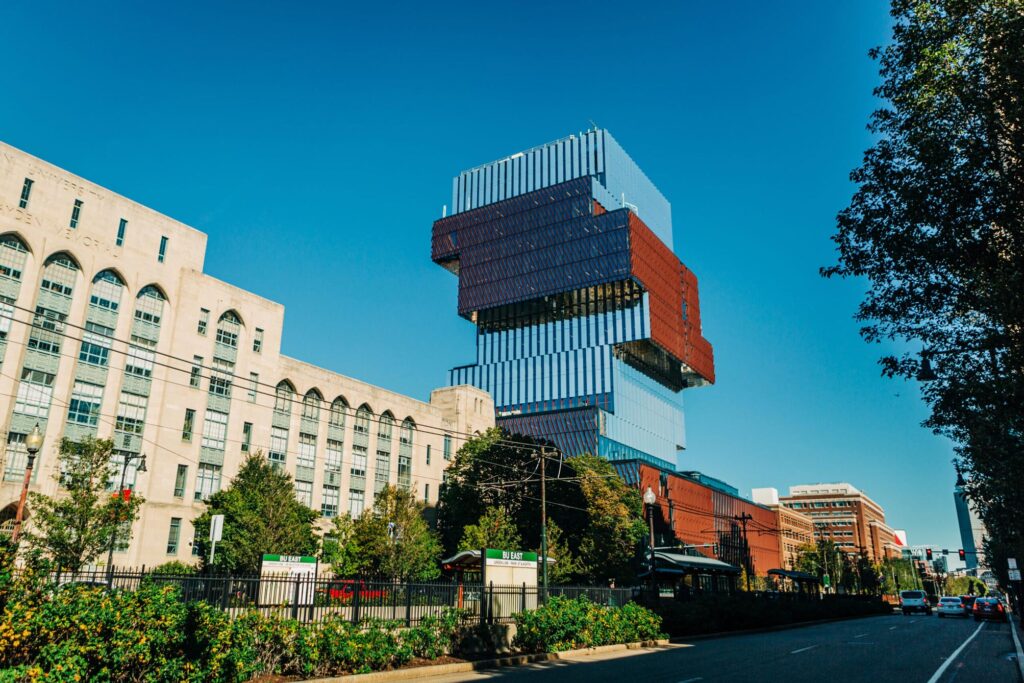Boston University’s Computing and Data Sciences Conference Center beside a traditional stone structure, set against a clear blue sky.