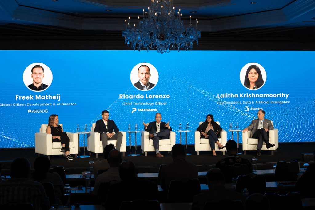 Five panelists are seated on stage in front of a blue screen displaying their names and titles, participating in a professional discussion at the BST Global AI Summit.
