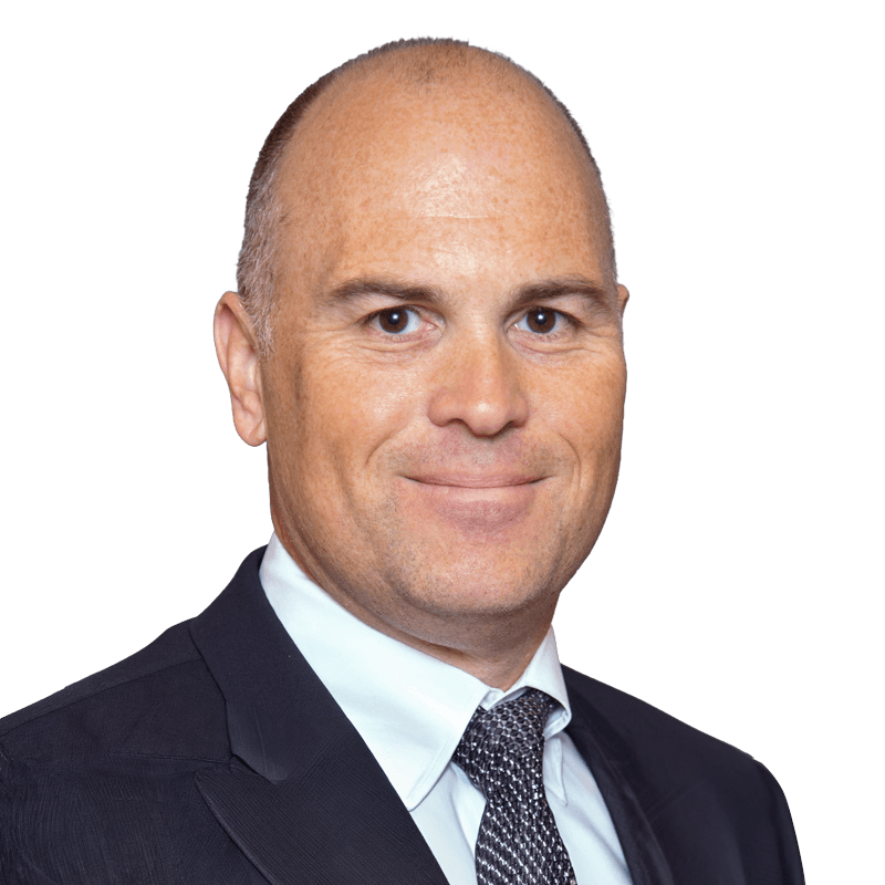 Philip-Townsend wearing a dark suit, white shirt, and patterned tie poses for a professional portrait against a plain white background.